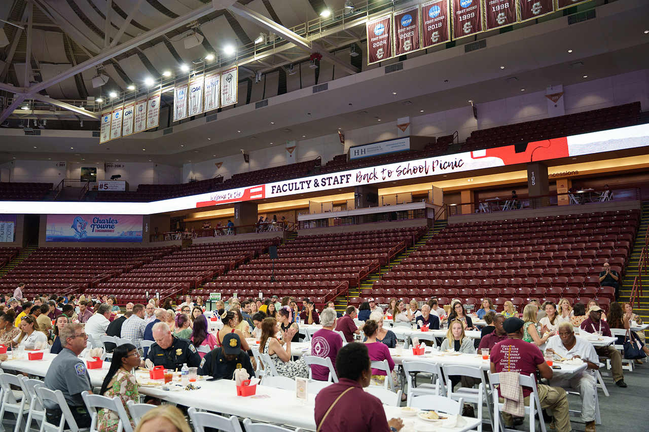 A large indoor arena filled with people seated at tables enjoying a 