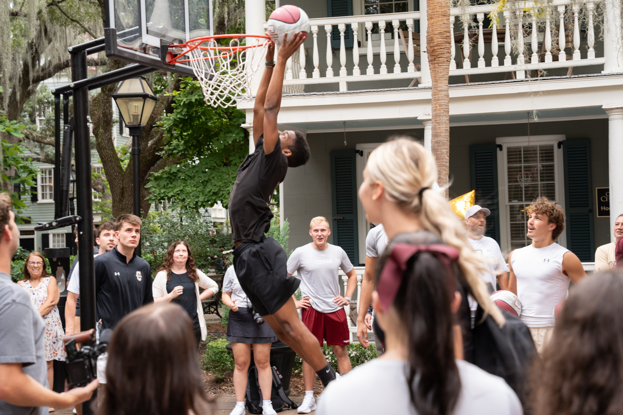 man jumps in air to shoot hoops outside