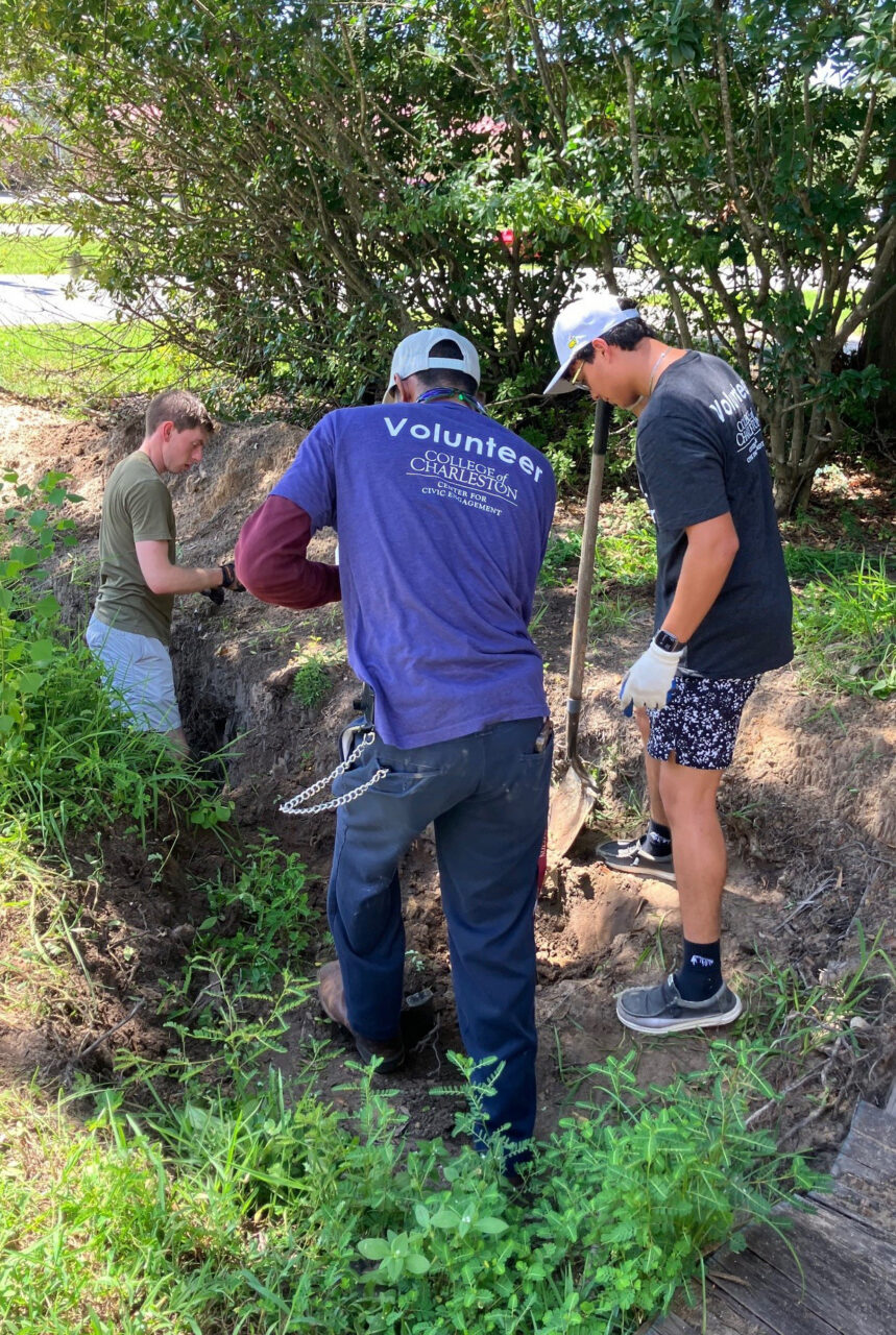 students and volunteers dig a ditch together