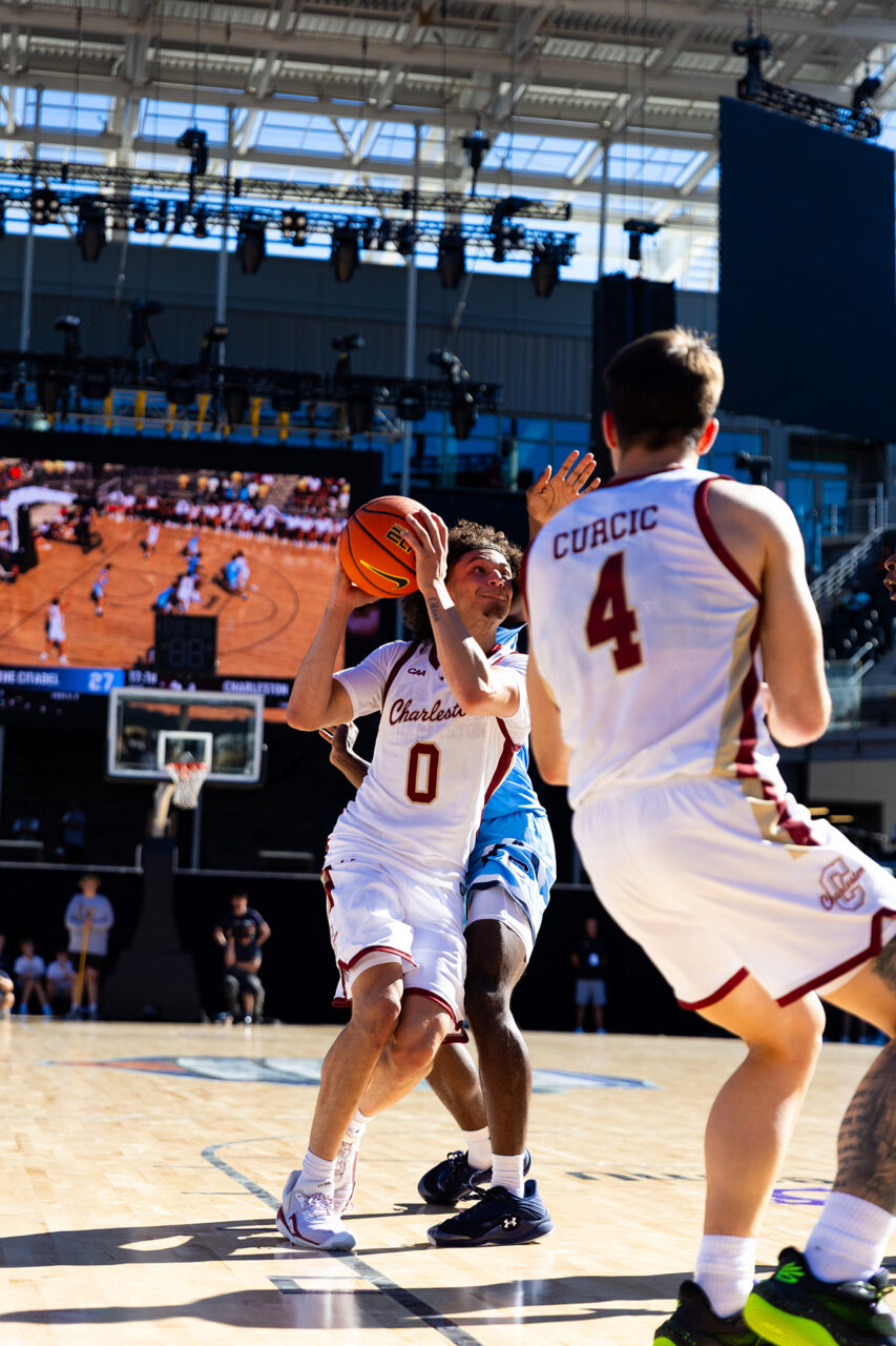 A basketball player in a white jersey with the number 0 prepares to shoot while being guarded by an opponent wearing a jersey with the name "Curcic" and the number 4.
