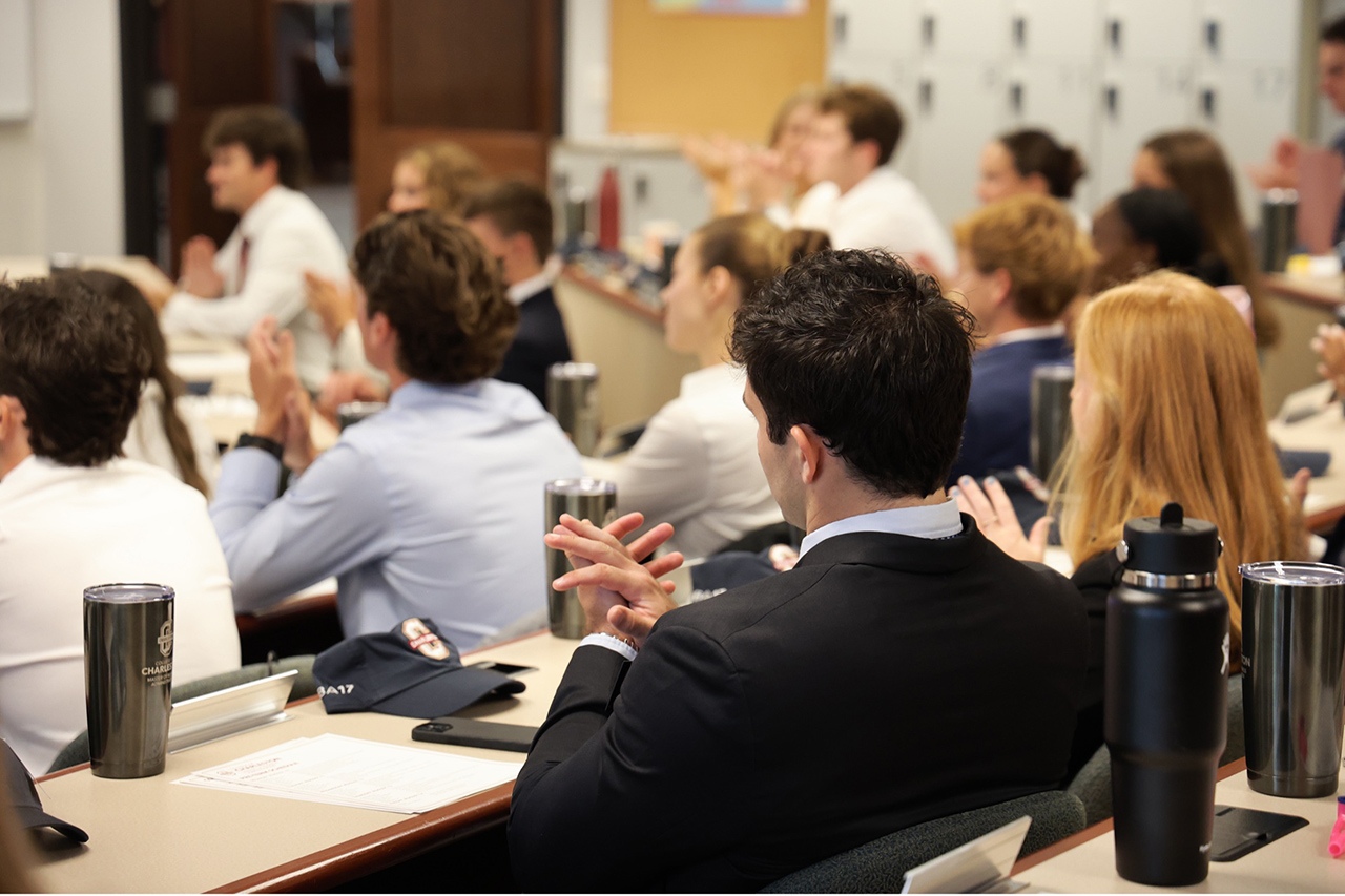 backs of students heads as they clap in a classroom